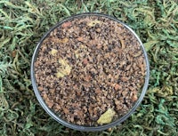a bowl of brown and black powder on top of green grass